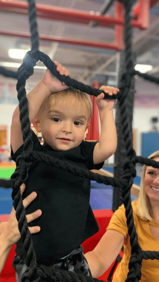 Toddler building climbing motor skills on the climbing ropes