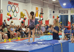 A girl posing after showcasing her gymnastics skills at the annual family expo.
